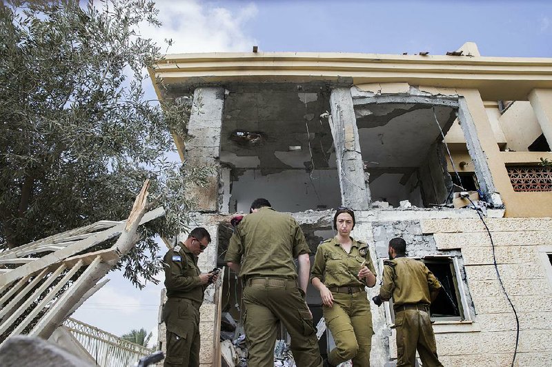 Israeli soldiers stand in front of a house in Beersheba, southern Israel, that was hit by a missile fired Wednesday from the Gaza Strip. 
