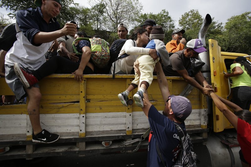 Honduran migrants bound to the U.S border climb into the bed of a truck in Zacapa, Guatemala, Wednesday, Oct. 17, 2018. The group of some 2,000 Honduran migrants hit the road in Guatemala again Wednesday, hoping to reach the United States despite President Donald Trump's threat to cut off aid to Central American countries that don't stop them. (AP Photo/Moises Castillo)