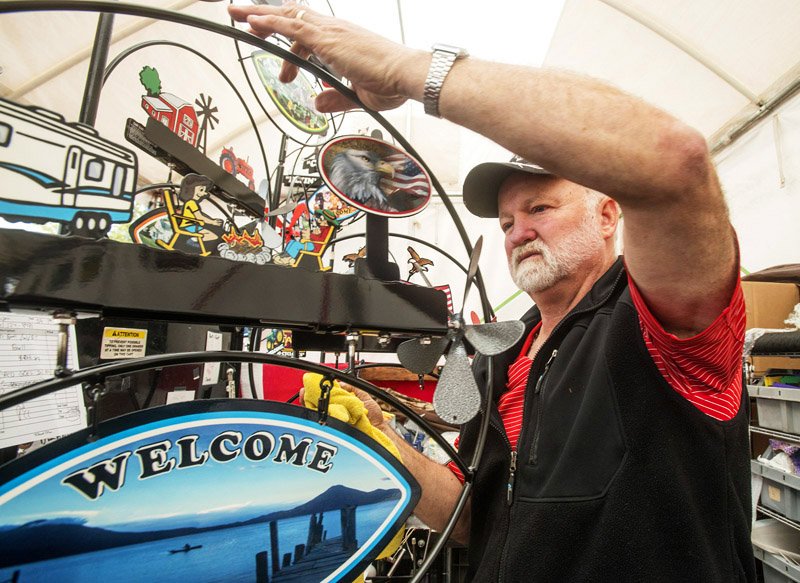 NWA Democrat-Gazette/BEN GOFF @NWABENGOFF Jim Kratzke of Metalcraft by K from Perham, Minn. personalizes a yard sign for a customer Thursday at the 50th annual Bella Vista Arts and Crafts Festival. Sponsored by the Village Art Club of Bella Vista, all proceeds from the festival support art education, including children's programs, scholarships and continuing education. The festival runs through Saturday.