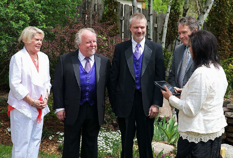 Jimmy Martin and Drew Jansen were married on May 24, 2014, at their home in Minneapolis. Pictured are (left to right) Jimmy’s best woman, Marcia Fluer, Drew’s best man, Peter Staloch, and their officiant, Patty Peterson. 