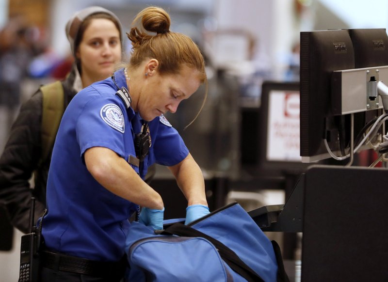 A Transportation Security Administration officer checks a traveler's bag at a screening location at Salt Lake City International Airport in Salt Lake City, Utah, on Dec. 23, 2016. 