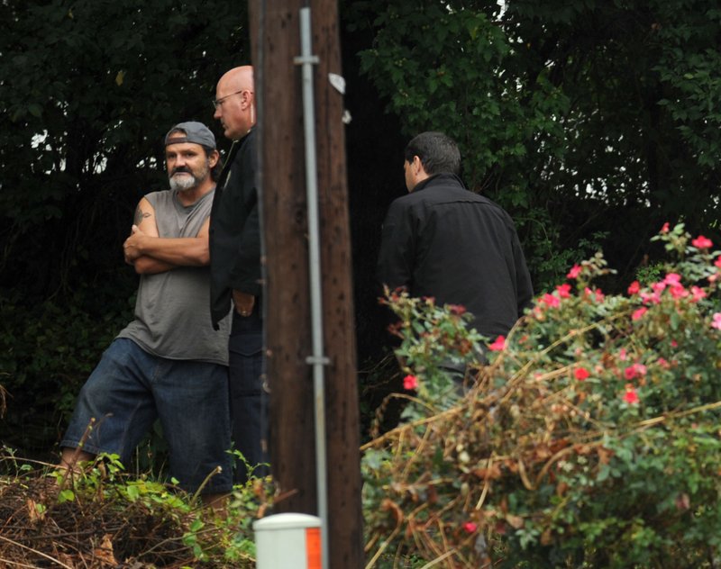 File Photo/NWA Democrat-Gazette/ANDY SHUPE Mark Chumley (left) speaks with Cpl. Robin Fields on Aug. 19, 2015, outside a house at 455 S. Hill Ave. after a caller reported a death at the residence. Chumley and four others were arrested on suspicion of capital murder, tampering with physical evidence and engaging in violent criminal group activity.