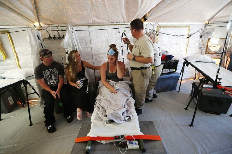 Corey Shuman and Amy Cross sit with Cross’ daughter, Aleeah Racette, as she  receives medical treatment Thursday in a disaster medical assistance tent outside a hospital in Mexico Beach, Fla., in the aftermath of Hurricane Michael. 
