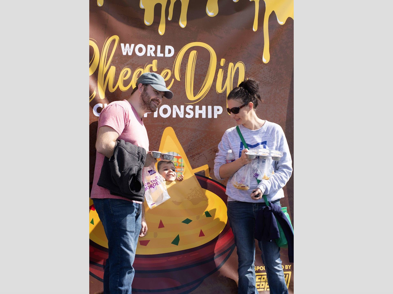 Visitors to the World Cheese Dip Championship in Little Rock pose in front of a sign at the event on Saturday.