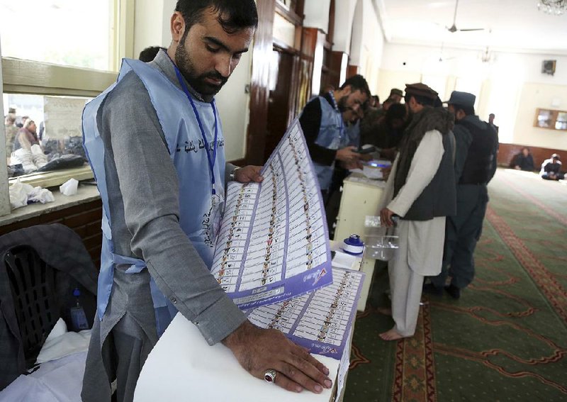 An Afghan election worker prepares ballots Saturday in Kabul for the country’s first parliamentary elections in eight years. Voting was disrupted by violence and chaos, with dozens of people dying in attacks and some key election workers failing to show up. Many polling places stayed open hours past the scheduled closing time to handle long lines of voters. 