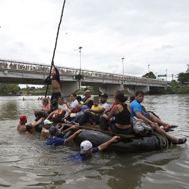 Central American migrants, part of a caravan trying to get to the United States, cross the Suchiate River between Guatemala and Mexico on Saturday at Ciudad Hidalgo, Mexico. Hundreds more wait on a bridge to get through a crossing checkpoint. About 2,000 migrants who circumvented Mexican police at the border voted to press on as a group and urged those still on the bridge to get across and join them. 