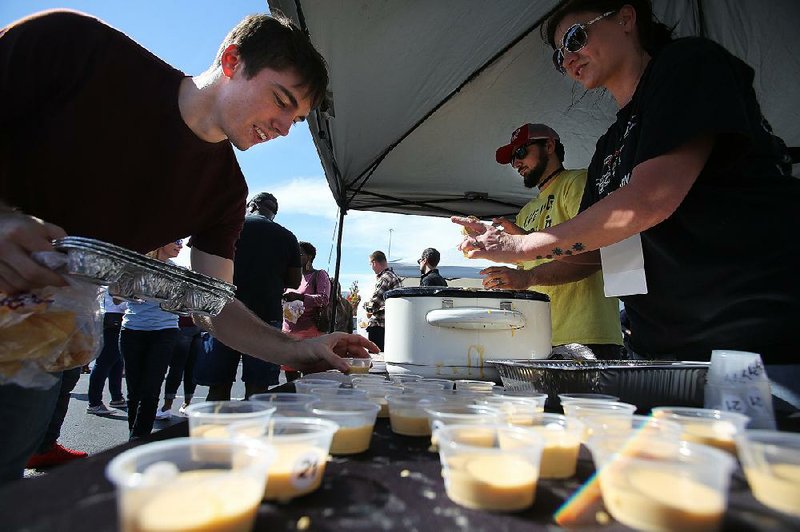 Andrew Lee of Russellville selects a cup of smoked cheddar queso from James and Laura Norman’s Food Geek Taco Company booth at Saturday’s competition in Little Rock.