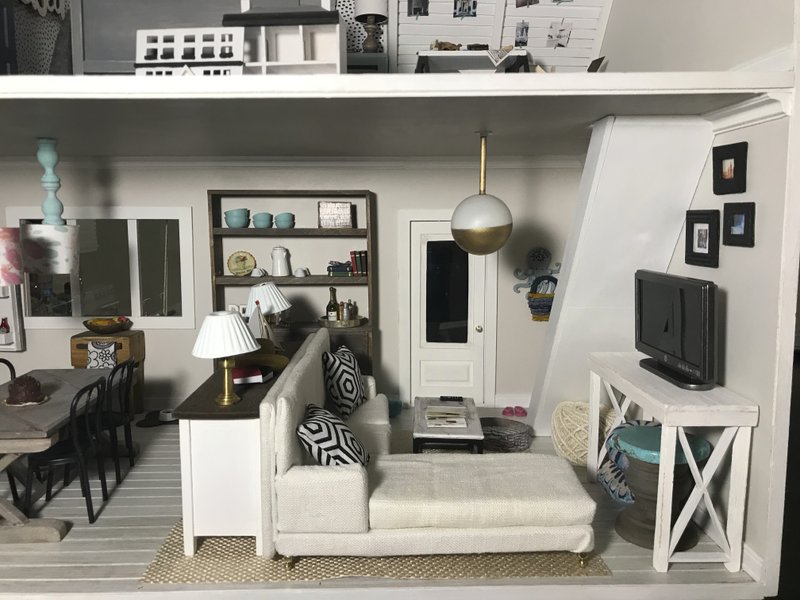 This 2018 photo provided by Amy Dorman shows the living room for the 144th scale dollhouse she created in Des Moines, Iowa. The art of dollhouse design has gotten big thanks to social media. Fans can share pictures of their miniature creations and draw inspiration from each other. And today's creations tend to feature a modern look. (Amy Dorman via AP)