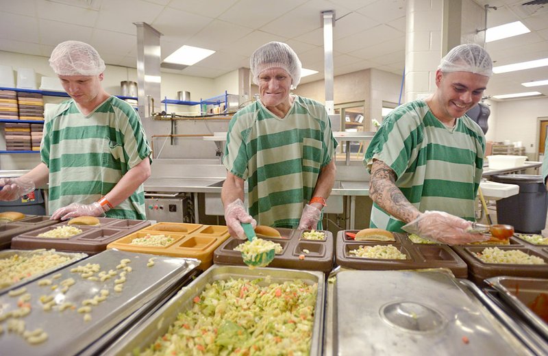 File Photo/NWA Democrat-Gazette/BEN GOFF Shawn Stoner (from left) of Fayetteville, Ronald Calhoun of Pea Ridge and Justin Teague of Fort Smith fill meal trays in 2015 as trustys prepare the evening meal at the Benton County Jail in Bentonville. A proposed $10 increase in jail fees will get Benton County near the break-even point for housing inmates, but costs are expected to keep increasing, county officials said.