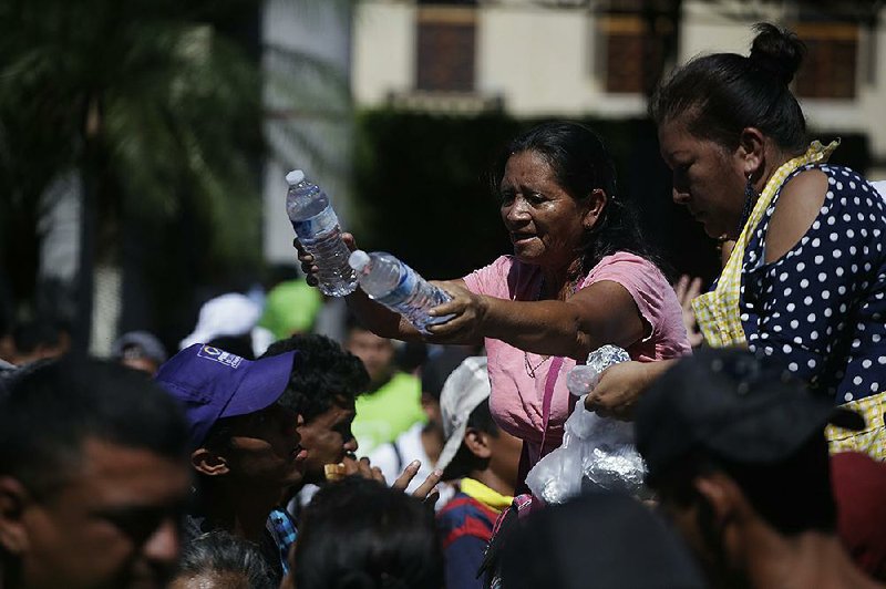 People in Tapachula, Mexico, hand out water bottles and sandwiches to migrants Monday as the caravan continues its journey to the U.S.