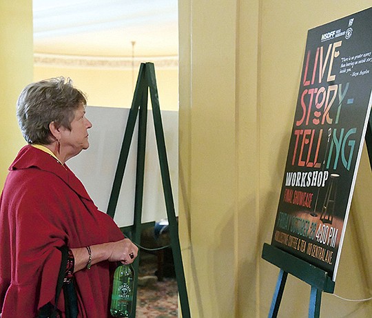 The Sentinel-Record/Grace Brown STORIES TO SHARE: Kristie Rosset, of Hot Springs, looks over a poster for a live storytelling workshop outside a cinema at the Hot Springs Documentary Film Festival Monday. The festival continues this week at The Arlington Resort Hotel &amp; Spa.