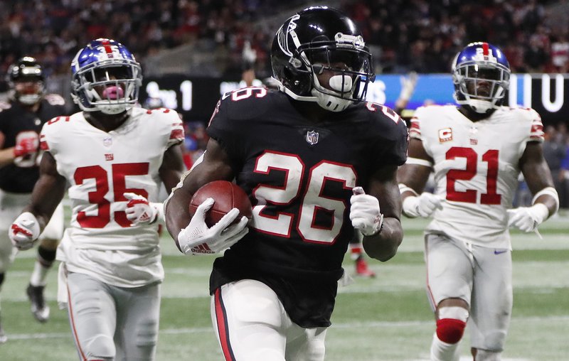 Atlanta Falcons running back Tevin Coleman (26) runs into the end zone for a touchdown against New York Giants free safety Curtis Riley (35) and strong safety Landon Collins (21) during the second half of an NFL football game, Monday, Oct. 22, 2018, in Atlanta. (AP Photo/John Bazemore)