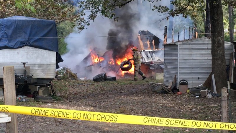 An unidentified firefighter tosses a tire away from a fire at 131 Lovia Circle Tuesday morning.