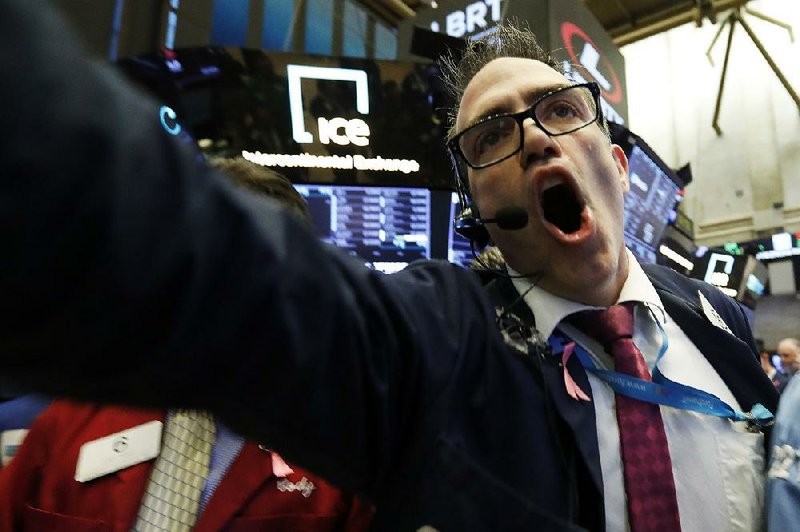 Trader Gregory Rowe works on the floor of the New York Stock Exchange on Tuesday, a day of heavy trading that began with the markets plummeting but clawing back most of the losses in the afternoon. 