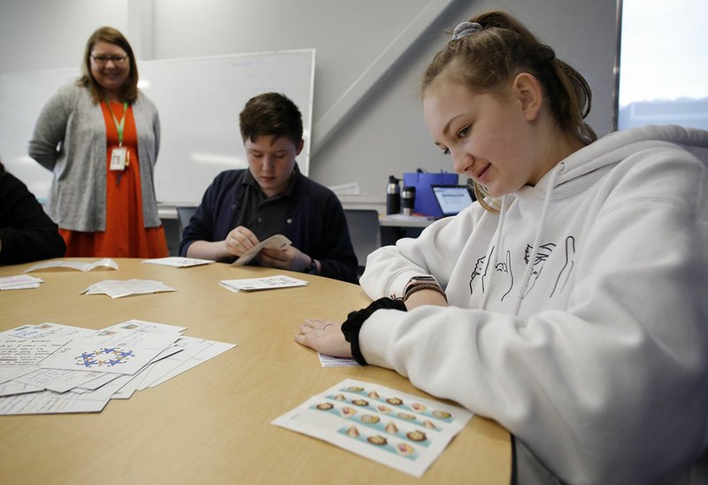 NWA Democrat-Gazette/DAVID GOTTSCHALK Madison Bolte, an eighth-grader at Arkansas Arts Academy, places stamps Tuesday on hand-made and addressed post cards in Amy Gillespie's Aspire class at the Rogers school. The students are sending the post cards to new registered voters to encourage them to vote. The project is part of a civics lesson on elections that include a study they looked at showing only 20 percent of voters younger than 25 typically turn out to vote.