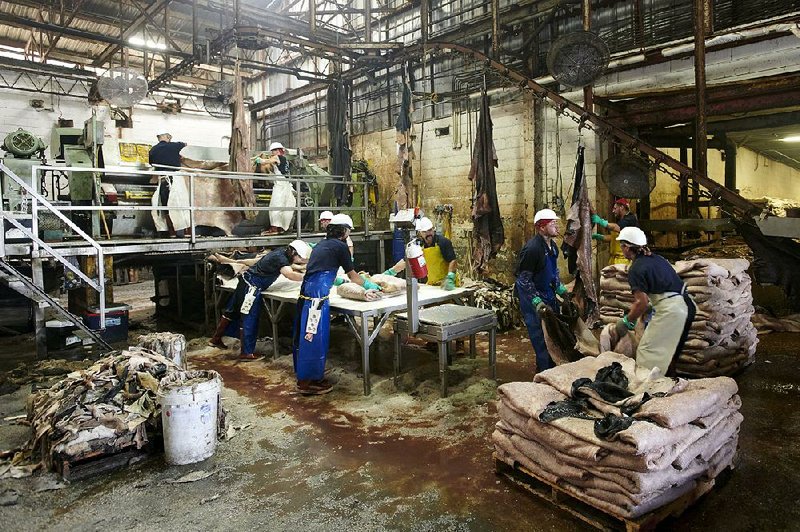 Workers clean and salt hides last month at the Texpac Hide and Skin Ltd. processing plant in Fort Worth. The U.S. trade deficit in goods widened in September, according to U.S reports. 