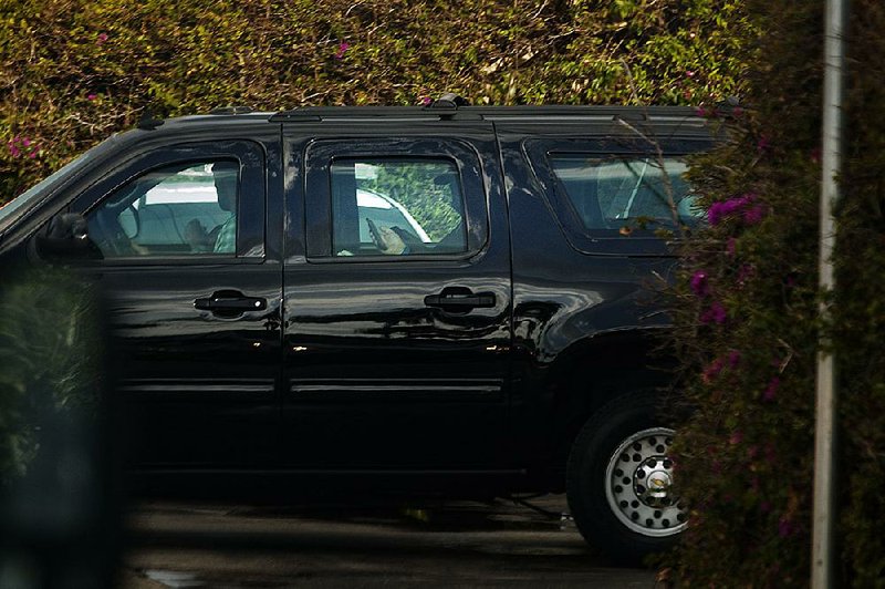 President Donald Trump (in back seat) uses a cellphone as his motorcade leaves his Mar-a-Lago resort in Florida on April 21. 