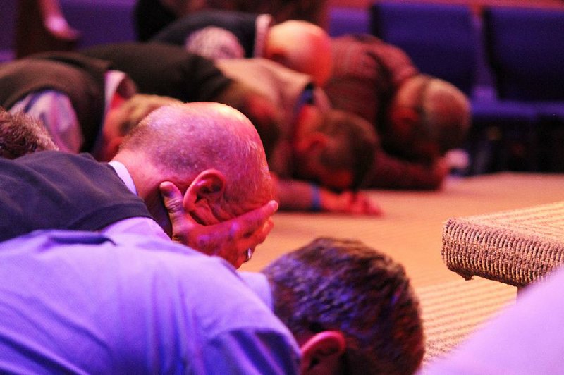 Attendees bow their heads in prayer at the front of the sanctuary of Central Baptist Church in Jonesboro on Monday during the Arkansas Baptist State Convention’s Pastors Conference. 