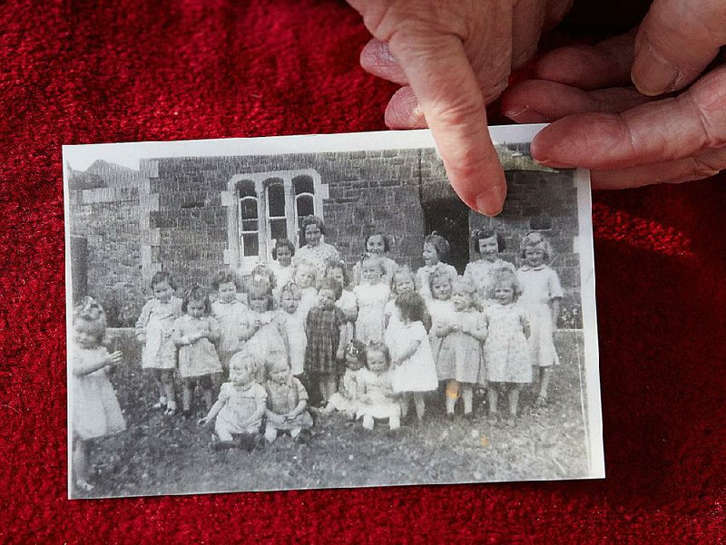 Elizabeth Coppin points to herself in a childhood photo outside Nazareth House industrial school in Tralee in County Kerry, Ireland, where she was kept from age 2-14 before being sent to a Magdalene laundry in Cork. 