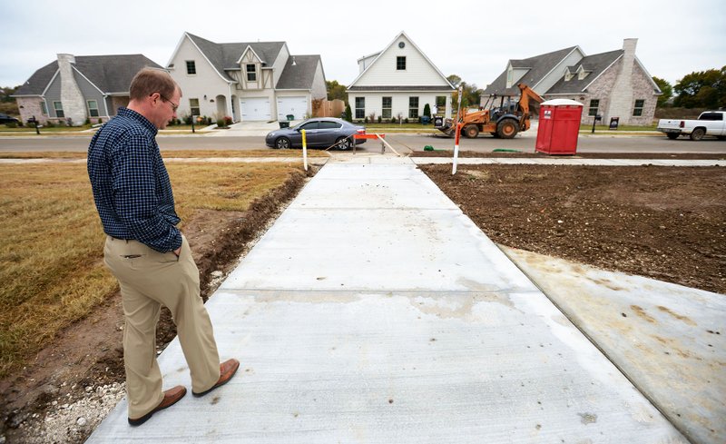 NWA Democrat-Gazette/ANDY SHUPE Aaron Wirth with Cobblestone Homes walks along a shared driveway Thursday behind a row of houses a subdivision being constructed south of Mountain Ranch in Fayetteville. The Brooklands subdivision will be built over multiple phases spanning several years. Phase I is under way with about 80 homes being built. Cobblestone Homes is the builder on the project.