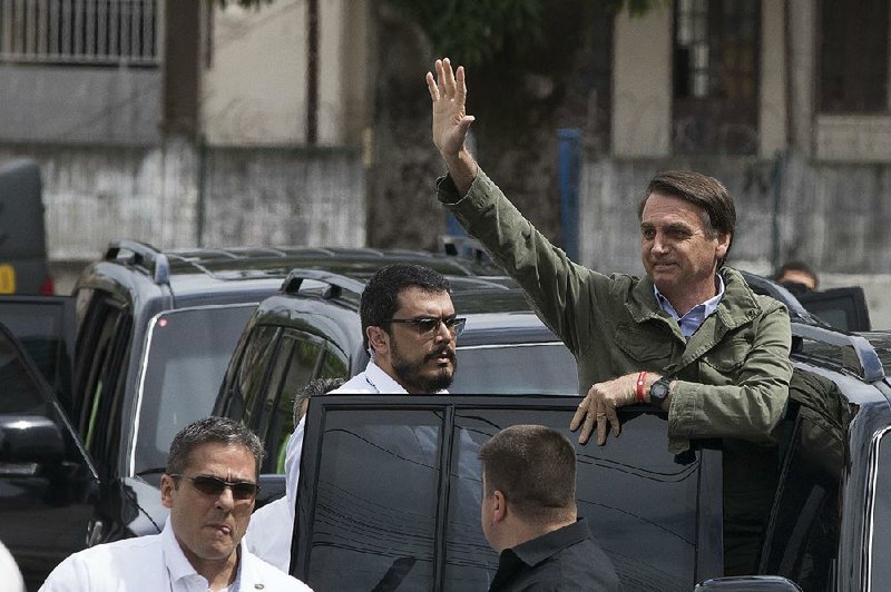 Brazilian presidential candidate Jair Bolsonaro of the far-right Social Liberal Party waves to supporters Sunday after voting at a polling station in Rio de Janeiro.