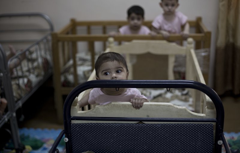 FILE - In this Aug. 15, 2018 file, photo, baby girls stand up in their cribs at Salhiya Orphanage, which now hosts foreign and Iraqi children of Islamic State militants, in Baghdad, Iraq. The enslavement of Iraqi Yazidi women by the Islamic State group has left a heartbreaking legacy -- hundreds of children fathered by militants. While some of the women want nothing to do with babies born of rape and slavery, some want to keep them, but they face rejection by families traumatized by the militants who killed hundreds of Yazidis and tried to wipe out the community. (AP Photo/Maya Alleruzzo, File)