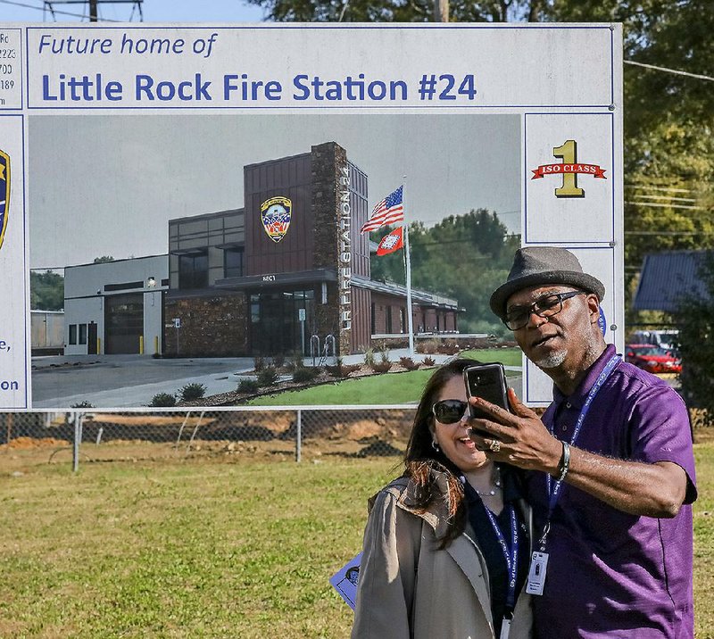 Little Rock city employees Doreen Mattes (left) and Chris Simmons pose for a selfie in front of a sign advertising the location for a new fire station. City officials held a groundbreaking ceremony Monday morning for Station 24 on Stagecoach Road in the southwest part of the city.