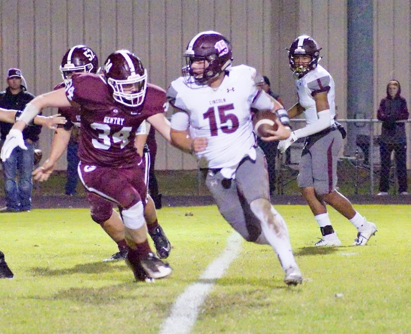 Westside Eagle Observer/RANDY MOLL Lincoln quarterback Caleb Lloyd carries the ball around the left side of the line while Gentry's Dylan Kilgore attempts to move in for a tackle during play in Pioneer Stadium against Lincoln High School on Friday, Oct. 26, 2018.