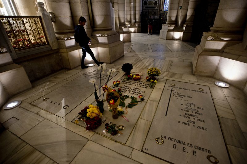 A person walks by the Franco family burial space adorned with flowers in the Almudena Crypt, a cavernous late-19th century Catholic temple under Madrid's Almudena cathedral, in central Madrid, Spain, Thursday Oct. 25, 2018. (AP Photo/Paul White)