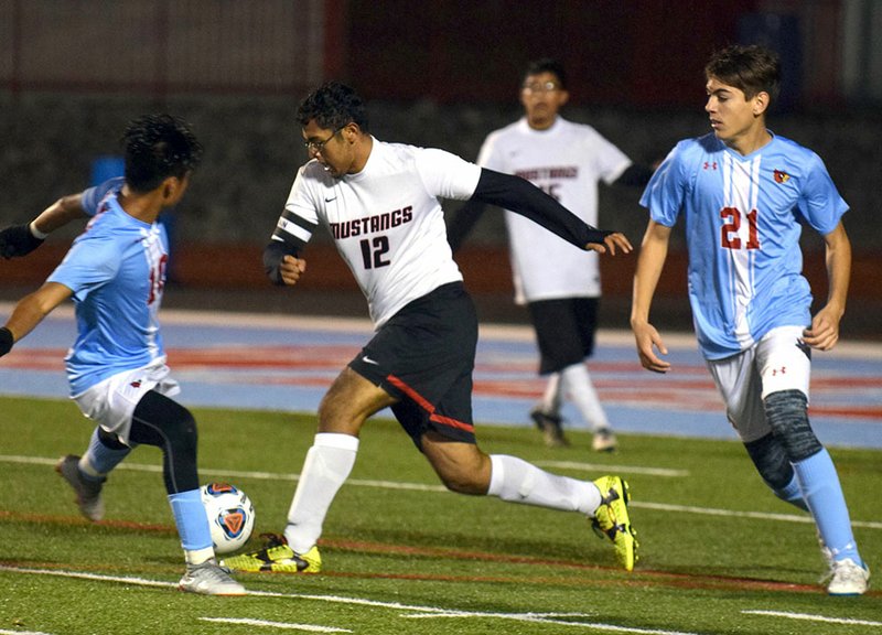 RICK PECK/SPECIAL TO MCDONALD COUNTY PRESS McDonald County's Francisco Jasso (12) splits Webb City's Manuel Cornelio (10) and Eythan Gilmore (2) during the Mustangs' 7-1 loss on Oct. 25 at Webb City High School. Jasso later scored McDonald County's lone goal in the match.