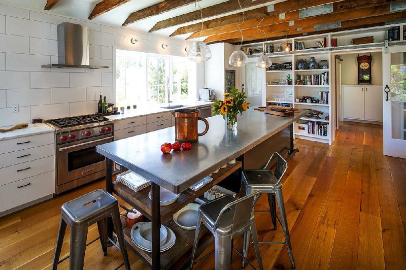 The bright, open great room is anchored by a sizable chef’s table with salvaged planks underneath. “It’s a workhorse of function, and reads like a piece of furniture,” says J.A.S. Design-Build designer Mike Freeman. The wall at the rear closes off to the private wing of the home. 