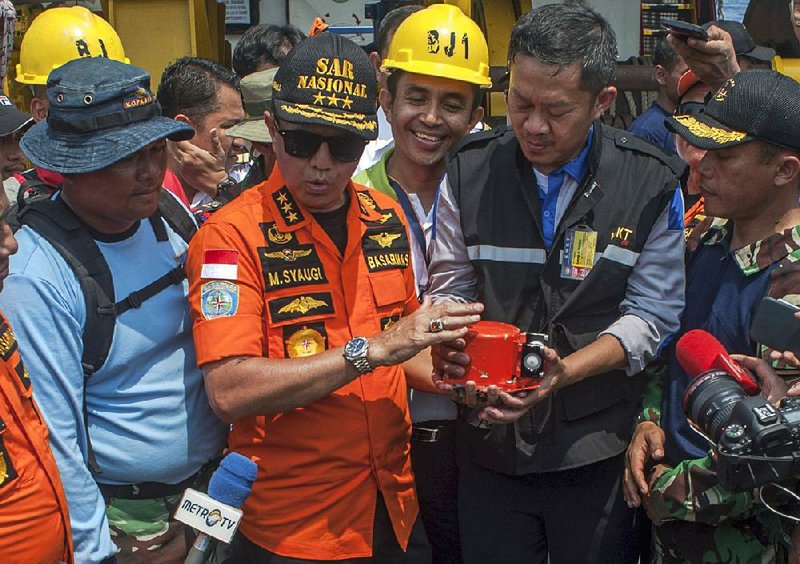 Muhammad Syaugi (second from left), head of Indonesia’s search and rescue agency, holds one of the data recorders from the crashed Lion Air jet Thursday after it was recovered in strong currents about 100 feet deep. 
