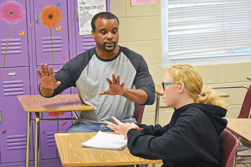 Jermaine “Jay” McClure of Little Rock encourages Keilee Fellows as she writes a poem in Leslie Travis’ seventh-grade class at Mountain Pine High School. A teaching artist with the Arkansas Learning Through the Arts program, McClure taught sessions on poetry and theater while he was at the local school.