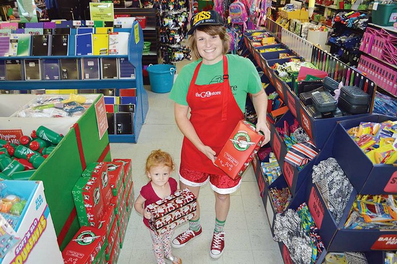 Erica Cason and her daughter, Josie, 2, hold shoeboxes available at the GO Store in downtown Conway. Cason and her husband, Andy, started the store to help fill the needs of Operation Christmas Child, in which shoeboxes full of supplies and toys are sent to 150 countries. Collection dates are Nov. 12-19, and more information is available at www.samaritanspurse.org/occ.