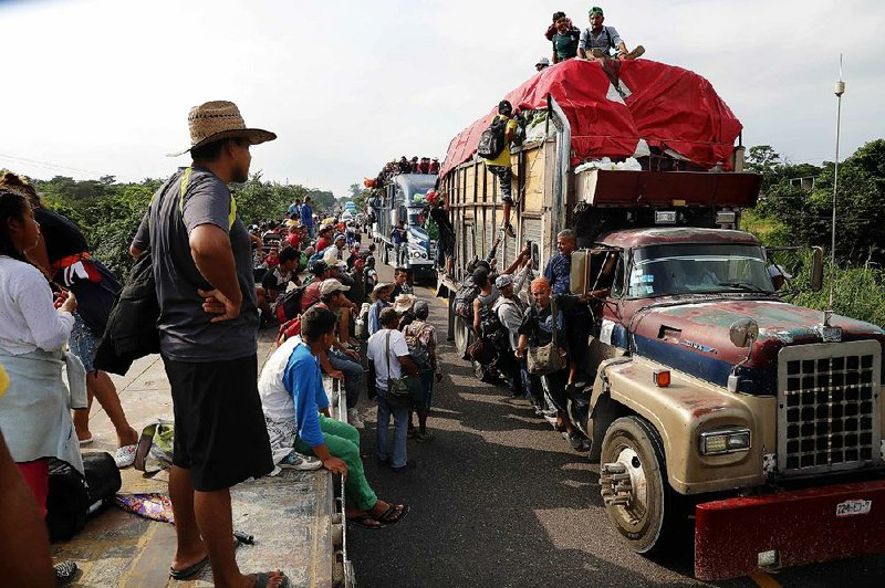 Central Americans, part of the caravan hoping to reach the U.S. border, hitch rides on trucks Friday in Donaji in Mexico’s Oaxaca state. 