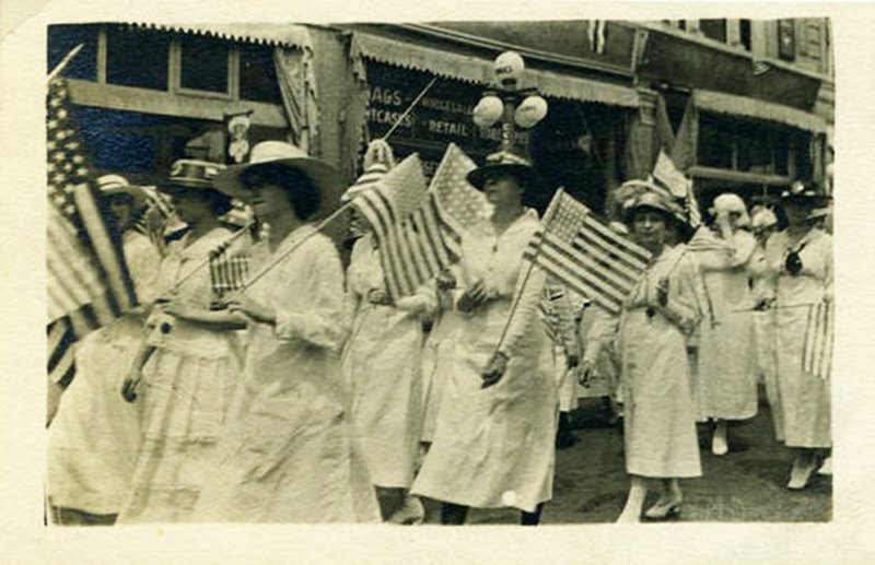 Women in white holding flags and marching on city streets, c. 1910-1920. … used with permission of Butler Center for Arkansas Studies
