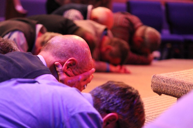 Arkansas Democrat-Gazette/FRANCISCA JONES Participants bow their heads in prayer at the front of the sanctuary of Central Baptist Church in Jonesboro during the Arkansas Baptist State Convention's Pastors Conference.