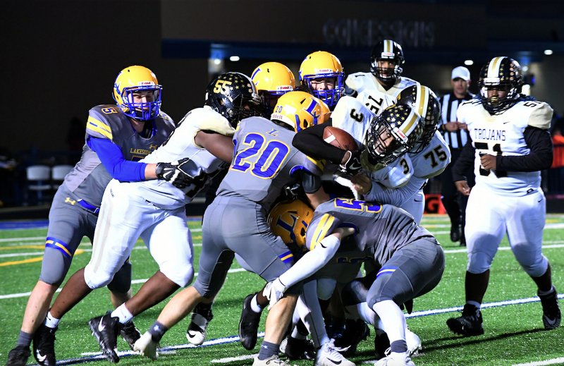 The Sentinel-Record/James Leigh CITY CHAMPIONSHIP: Hot Springs senior running back Damien Walker (3) is stopped by Lakeside senior linebacker Reece Turner (20) and other Rams on defense Friday as the Trojans fell, 35-32, on the road at Chick Austin Stadium.