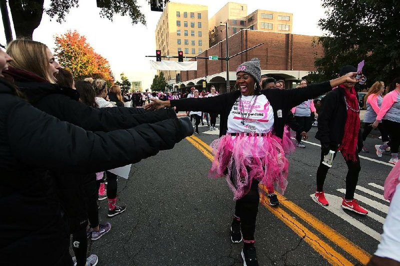 Eve Geiggar high-fives supporters as she makes her way Saturday along Little Rock’s Main Street during the 25th annual Susan G. Komen Arkansas Race for the Cure. More photos are available at arkansasonline.com/raceforthecure.