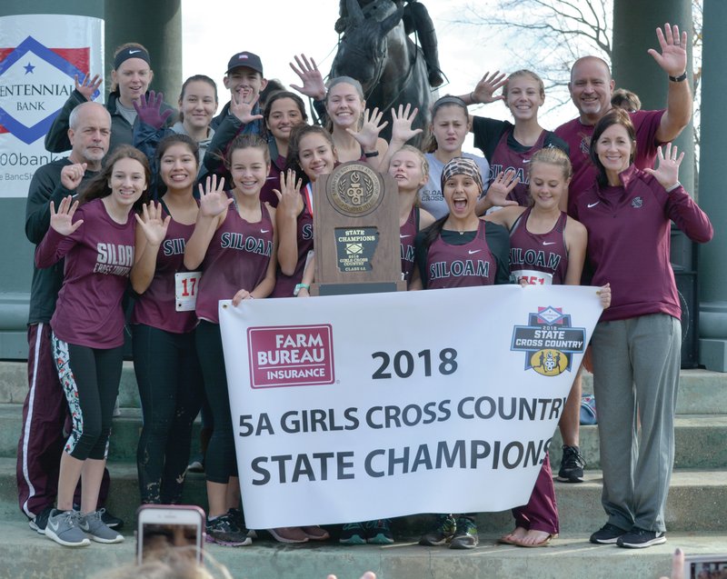 Graham Thomas/Siloam Sunday The Siloam Springs girls cross country team and coaches celebrate on the winner's podium Friday after winning the Class 5A Girls State Cross Country Meet at Oaklawn Park in Hot Springs. The state title is the Lady Panthers' fifth straight after winning the previous four in the former Class 6A classification.