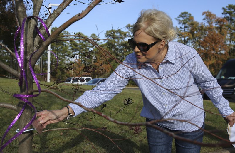 Laurie Jernigan, mother of Ebby Steppach, adjusts a plaque after the dedication ceremony for the tree planted in Steppach's honor on Sunday, Nov. 4, 2018, at Chalamont Park in Little Rock.