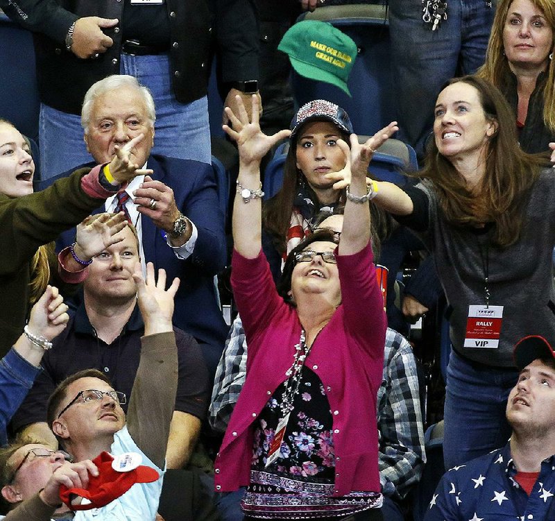 People reach for a cap thrown into the crowd before the start of a rally Sunday with President Donald Trump in Chattanooga, Tenn. Trump was in Tennessee to campaign for Republican Marsha Blackburn in her bid for the U.S. Senate. 