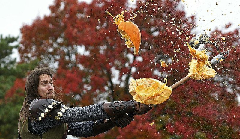 Edward Maciejczyk destroys a tossed pumpkin as he and other knights at Medieval Times in Schaumburg, Ill., use weapons to destroy leftover Halloween pumpkins and jack-o-lanterns Monday.