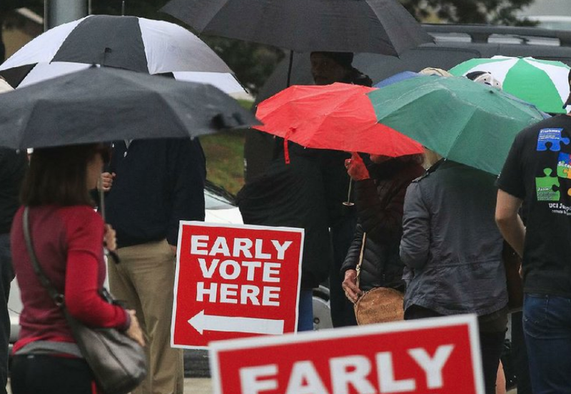 Voters take shelter under umbrellas as they wait in line Monday to vote at the Pulaski County Regional Building on the final day of early voting. Polls open again across the state at 7:30 a.m. today. 
