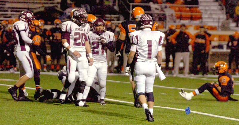 MARK HUMPHREY ENTERPRISE-LEADER Lincoln defenders (from left): linebacker Tyler Cummings (No. 20), linebacker Johnny Yang (No. 21), and cornerback Patrick Haynes (No. 1), prepare to come off the field following a successful fourth-down stand on the road at Malvern. The Wolves beat the Leopards, 41-21, with opportunistic defensive plays on Nov. 22, 2018, Lincoln's last playoff win. On Friday, Lincoln has opportunity to update its playoff portfolio playing on the road at Hamburg. Kickoff is 7 p.m. Friday.