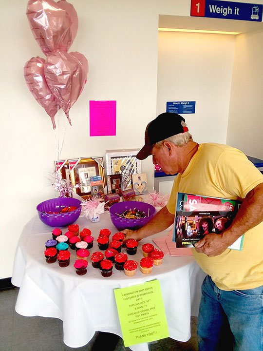 MARK HUMPHREY ENTERPRISE-LEADER Postal patron Dan Daniel, of the Farmington area, selects a cupcake during "Customer Appreciation Day," held Tuesday, Oct. 30, 2018, at the Farmington Post Office in recognition of more than $2,500 in local sales of pink stamps, a portion of which is devoted to fund breast cancer research.