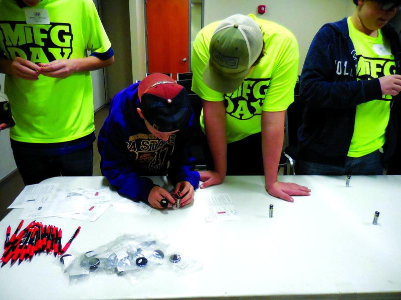 Horizontal: Students from Junction City High School work together to use a battery and magnets to trigger a coil to spin while in the break out session with Entergy representatives.