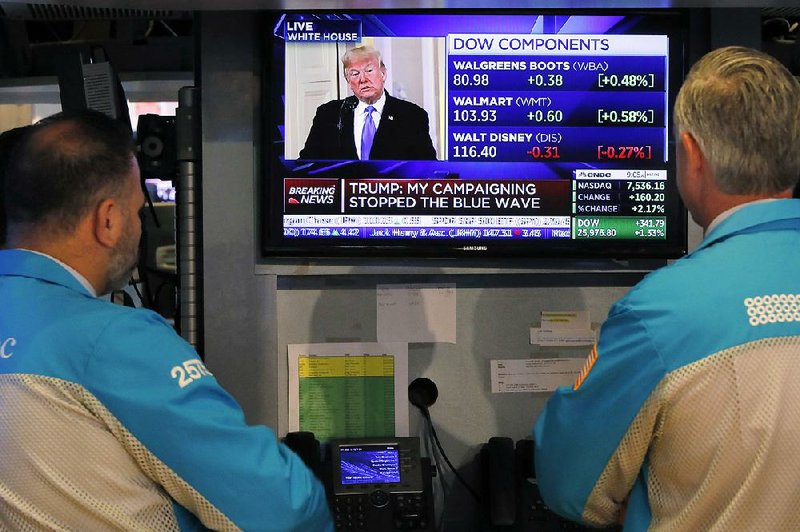 Specialists on the floor of the New York Stock Exchange watch President Donald Trump’s news conference Wednesday. Major U.S. stock indexes soared Wednesday. 