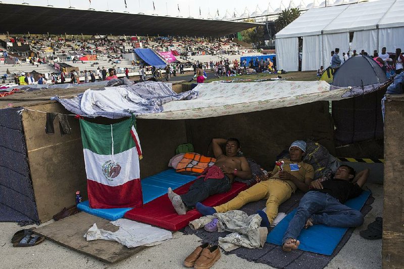 Central American migrants, part of a caravan of people heading north toward the U.S., rest Tuesday in the Jesus Martinez stadium in Mexico City.