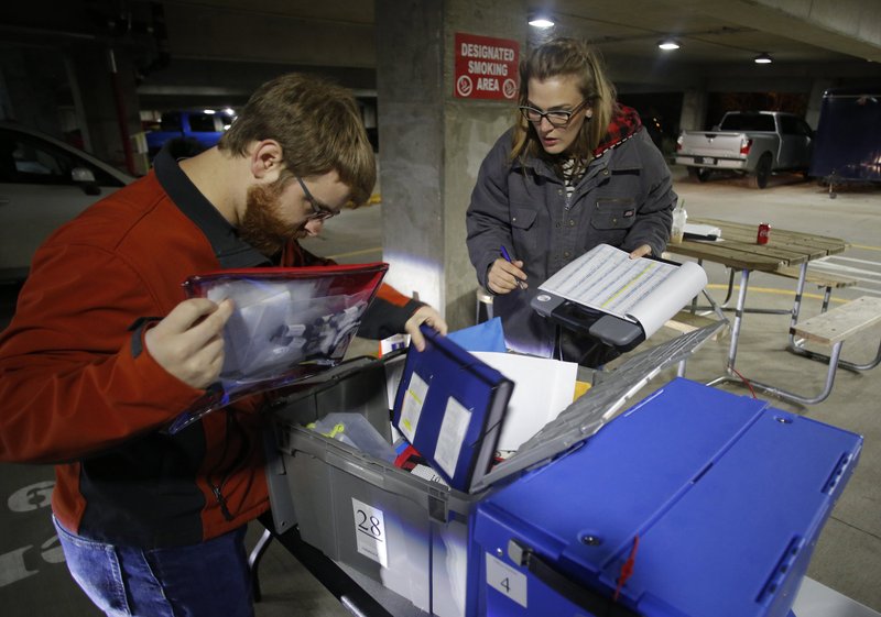 NWA Democrat-Gazette/DAVID GOTTSCHALK Laura Shepard-Johnson (right) with the Washington County Election Commission takes inventory Tuesday of election equipment from voting centers as it arrives back at the Washington County Courthouse in Fayetteville. Equipment and ballots were being collected from 47 voting centers in the county.